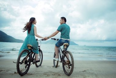What women need in a relationship shows a couple cycling on the beach.